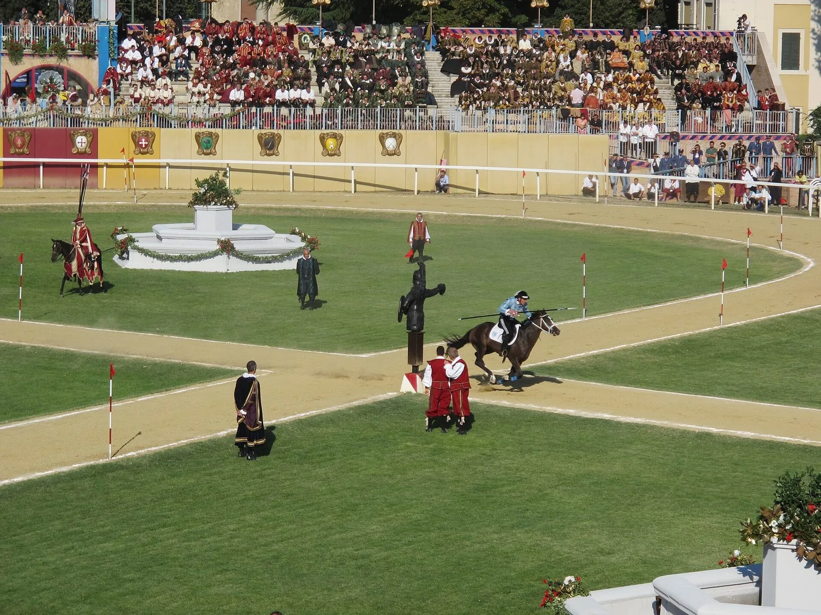 Un cavaliere al galoppo infila l'anello davanti alla statua del Quintano durante la Giostra della Quintana di Foligno